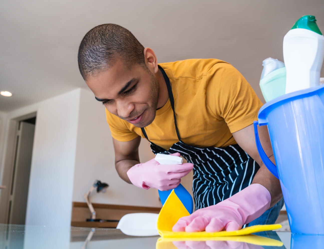 Close up of young latin man cleaning stains off the table at home. Housekeeping and cleaning concept.